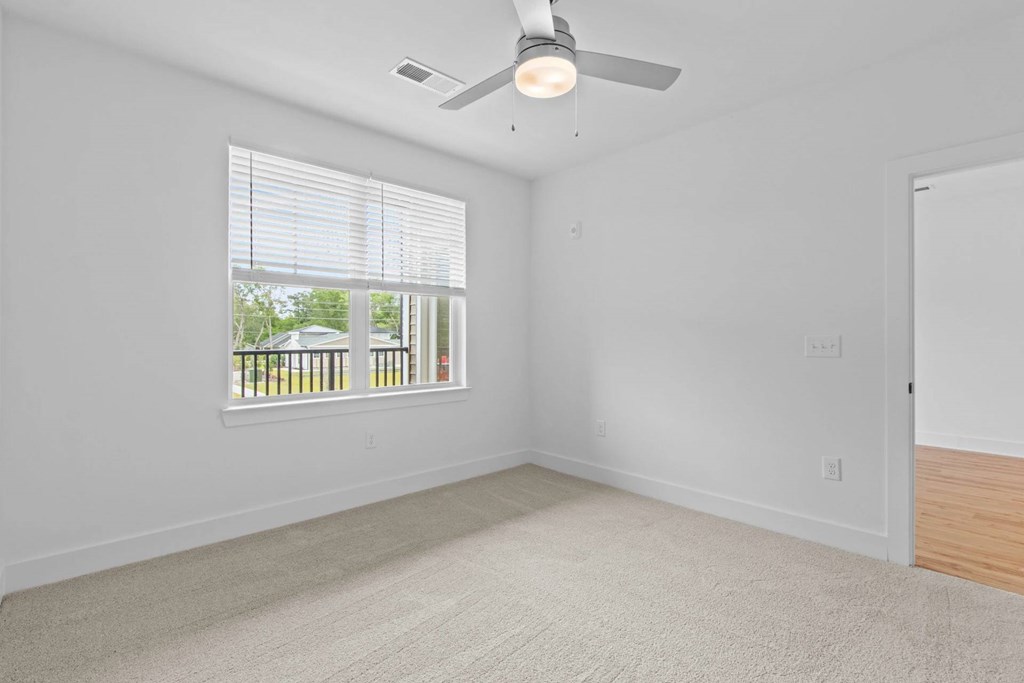 A room with a ceiling fan and a window with blinds.