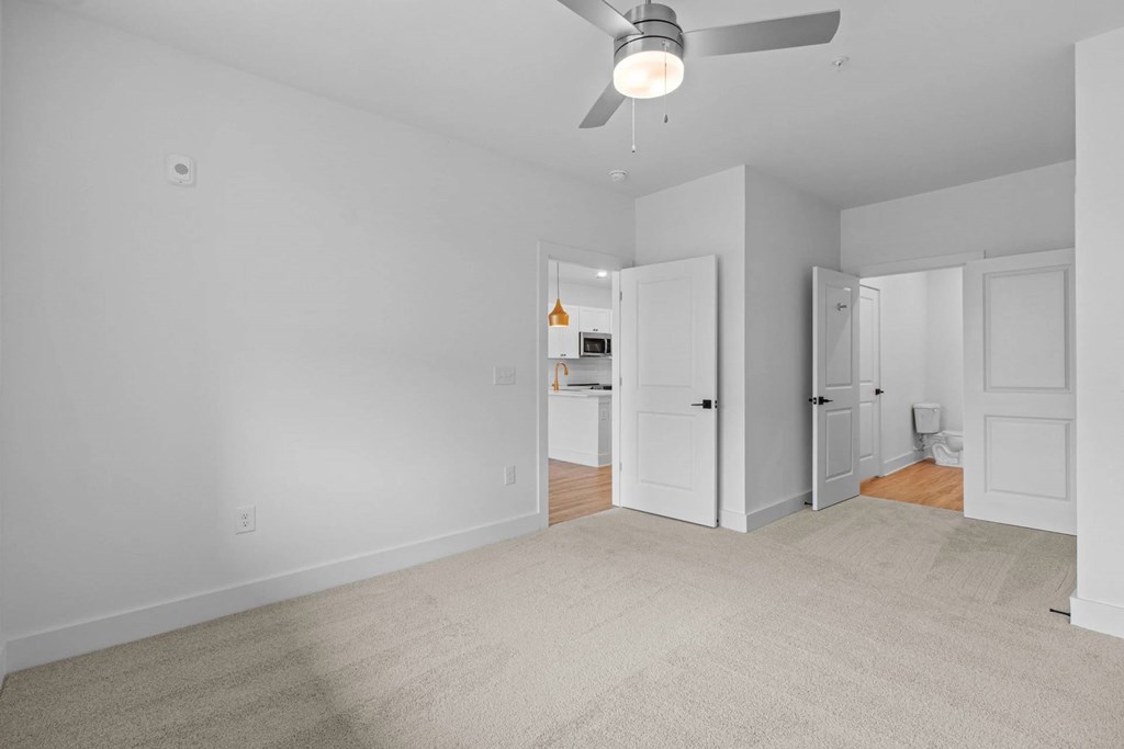 A room with a ceiling fan and carpeted floor.