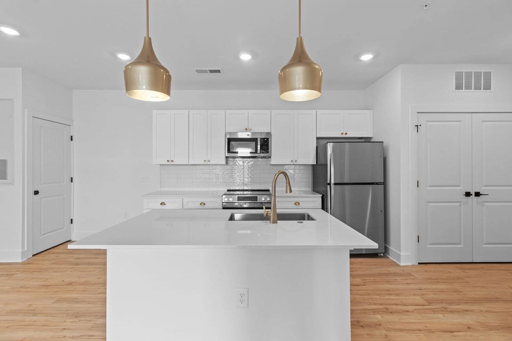 A modern kitchen with a white countertop and stainless steel appliances.
