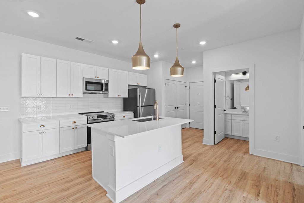 A modern kitchen with white cabinets and a wooden floor.