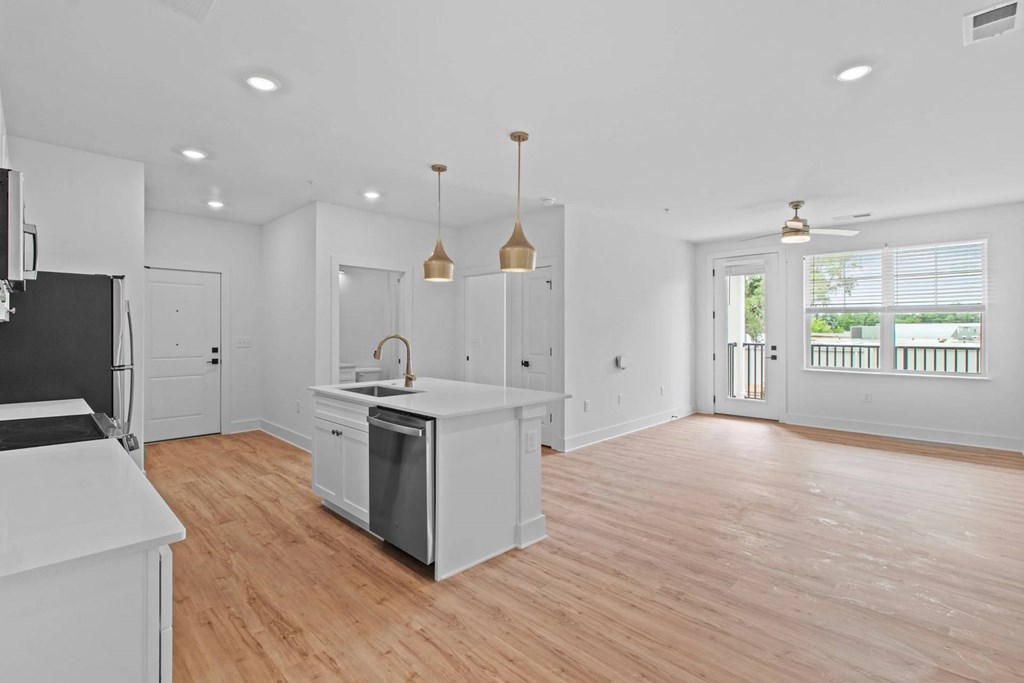 A kitchen with white cabinets and a wooden floor.