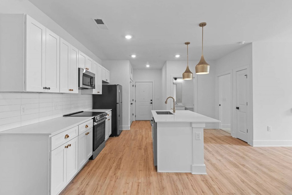 A kitchen with white cabinets and a black fridge.
