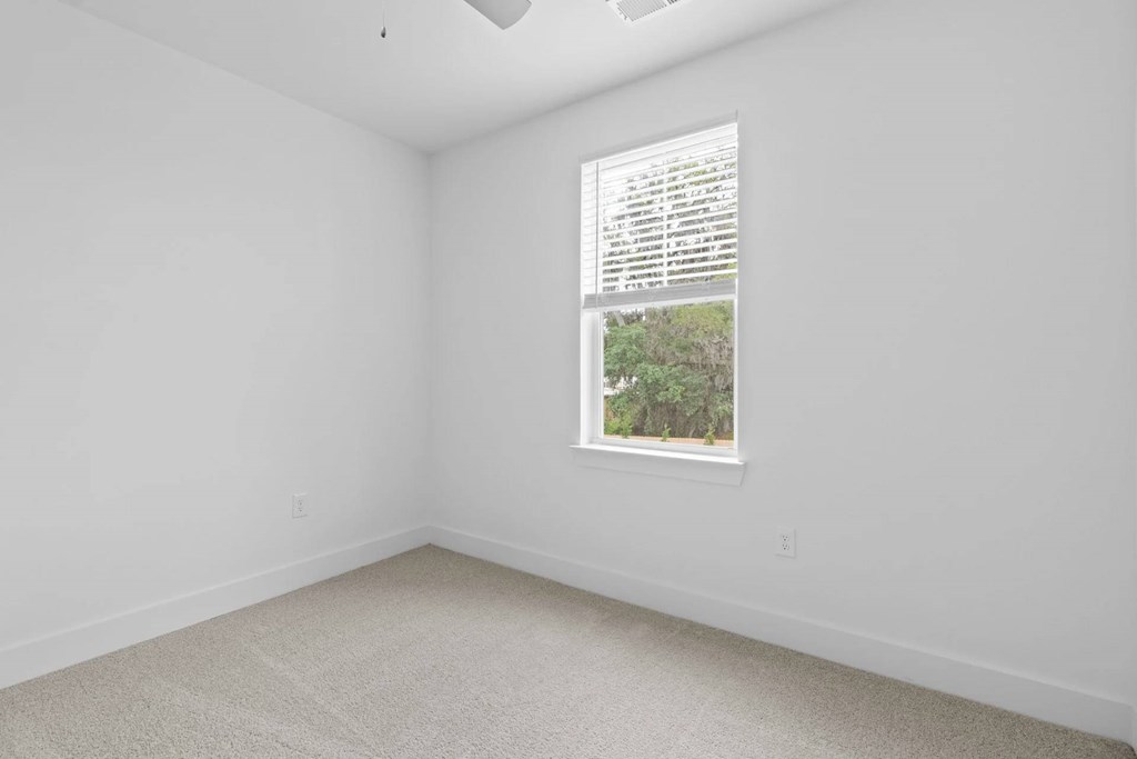 A room with a window showing a view of trees.