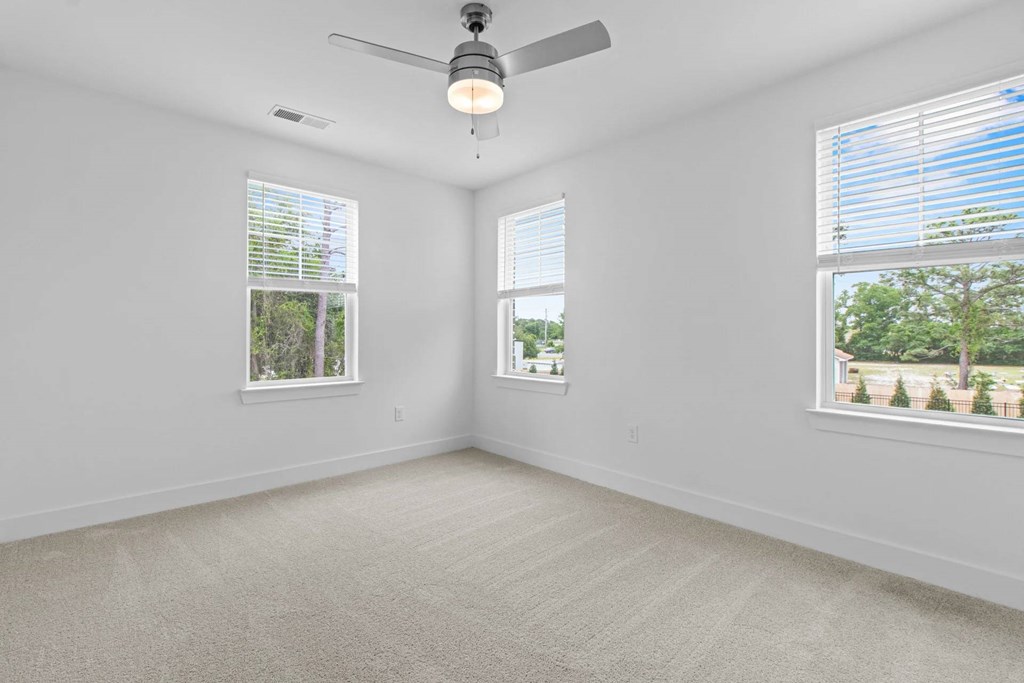 A room with a ceiling fan and two windows.