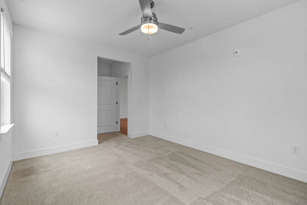 A room with a ceiling fan and carpeted floor.