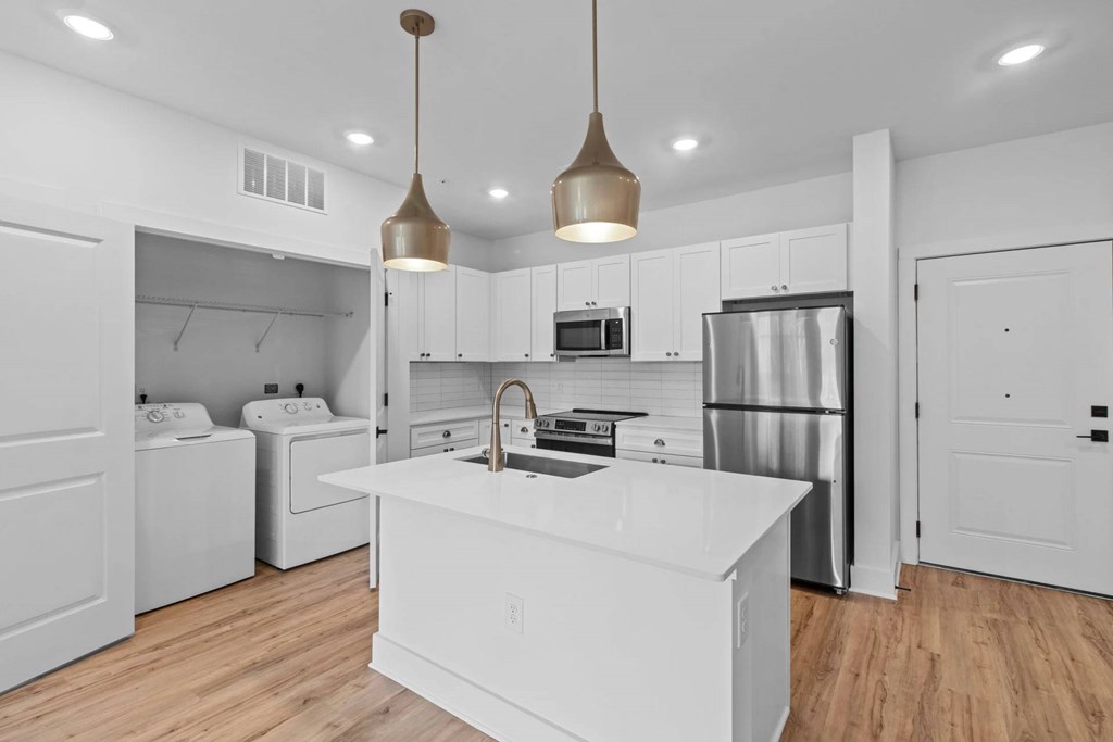 A modern kitchen with a white island and stainless steel appliances.