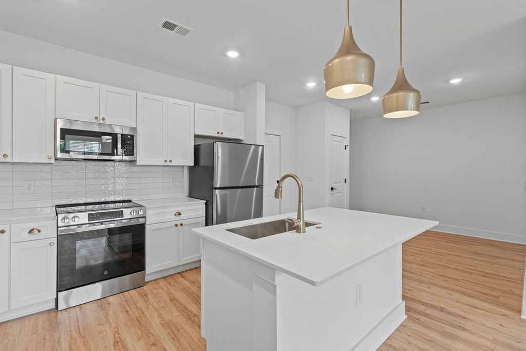 A kitchen with white cabinets and a white island.