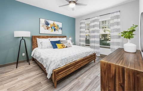 A bedroom with a bed, a side table, and a painting on the wall.
