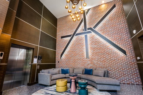 A modern living room with a grey couch and a brick wall.