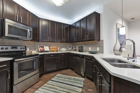 A modern kitchen with dark brown cabinets and stainless steel appliances.