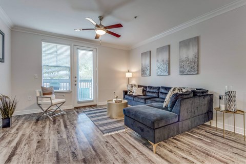 A living room with a blue couch and a ceiling fan.
