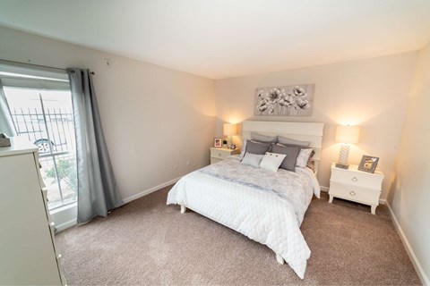 A bedroom with a large bed and a window with curtains.