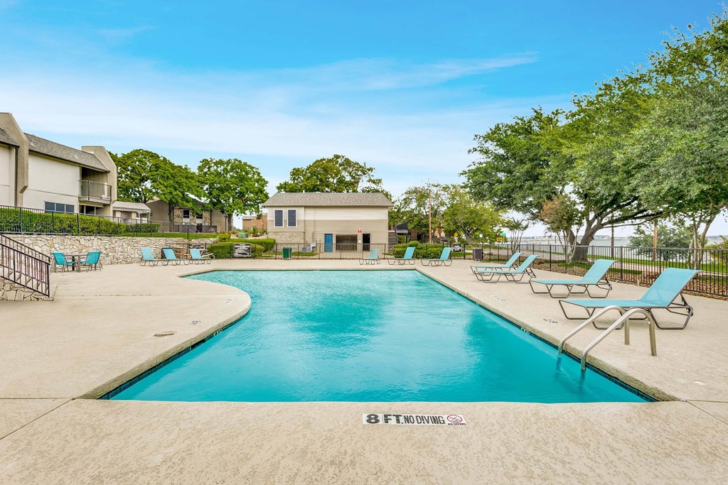A large swimming pool with lounge chairs and a building in the background.