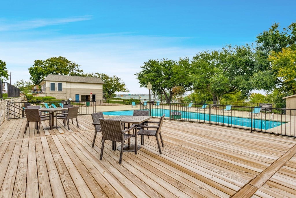 A wooden deck with chairs and a pool in the background.