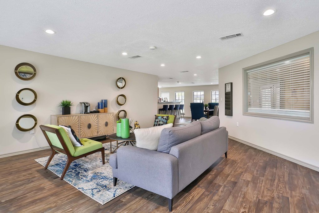 A living room with a grey couch, a green chair, and a wooden cabinet.