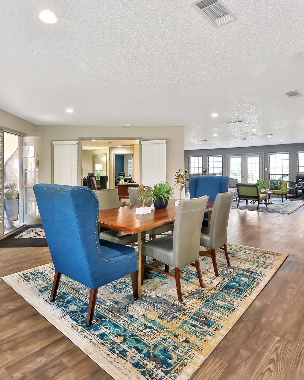 A dining room with a blue chair and a rug.