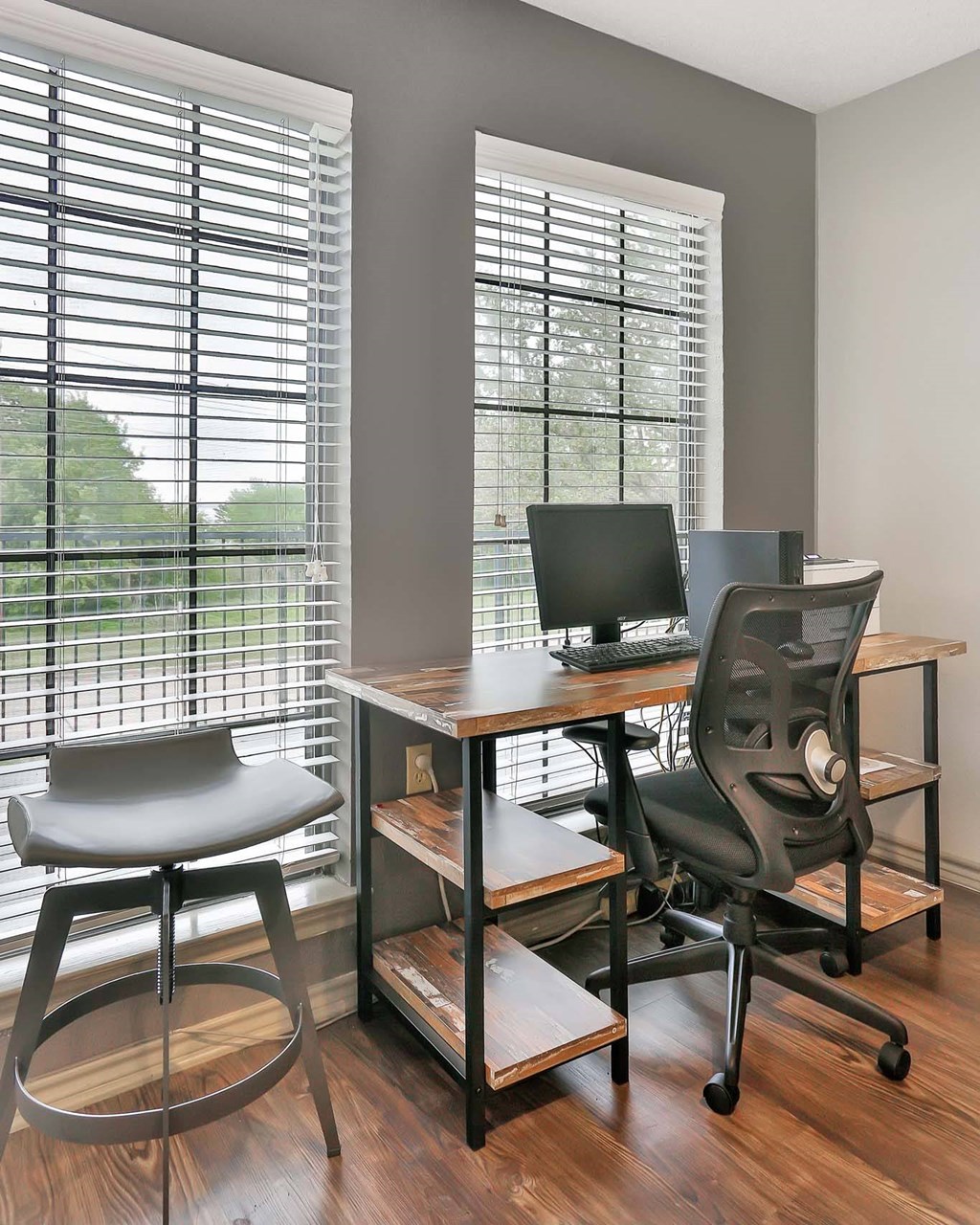 A black chair sits in front of a desk with a laptop on it.