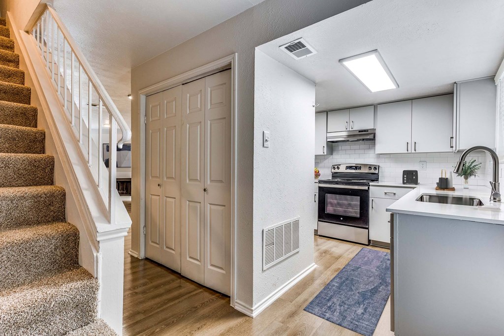 A white kitchen with a staircase leading to the upper floor.