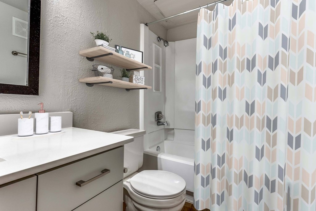 A bathroom with a toilet, sink, and shower curtain.