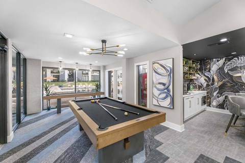 A pool table is in the middle of a room with a ceiling fan and a chair.