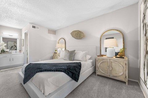 A bedroom with a bed, nightstand, and a mirror.