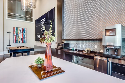 A modern kitchen with a pool table in the background.