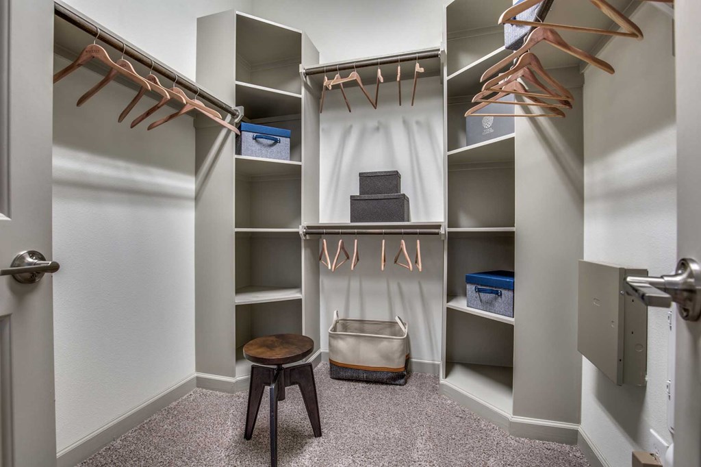 A walk in closet with a bench and a bag on the floor.