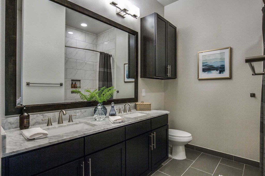 A bathroom with a marble countertop and black cabinets.
