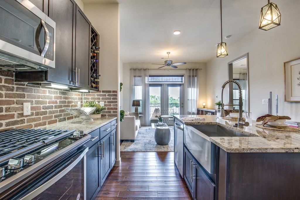 A modern kitchen with dark wood floors and stainless steel appliances.