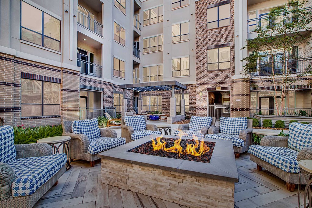A patio with a fire pit and chairs.