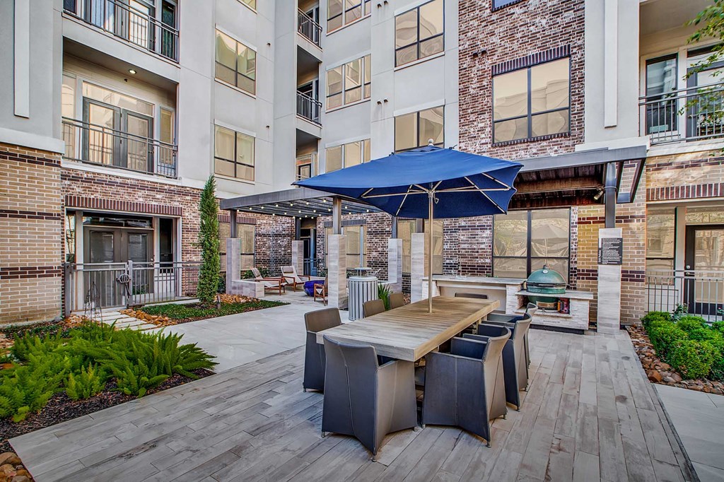 A patio with a table and chairs under a blue umbrella.