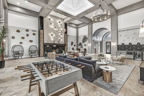 A foosball table is in the middle of a living room with a couch and a fireplace.