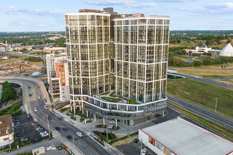 A large glass building is surrounded by roads and other buildings.