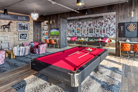A pool table is in the middle of a room with a dart board on the wall.