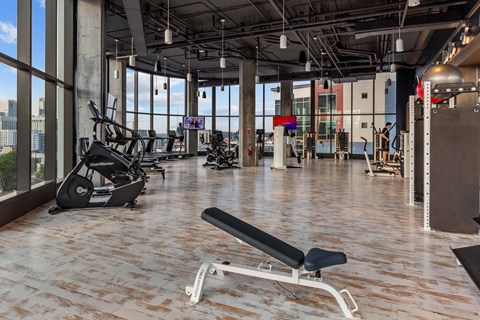A gym with a row of treadmills and a bench in the foreground.