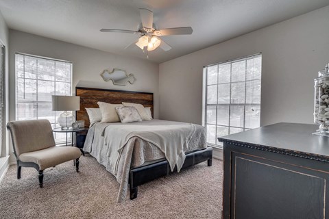 A bedroom with a bed, chair, and a ceiling fan.