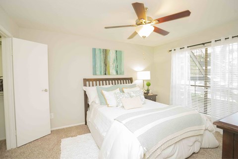 A bedroom with a large bed and a ceiling fan. Un dormitorio con una cama grande y un ventilador de techo.