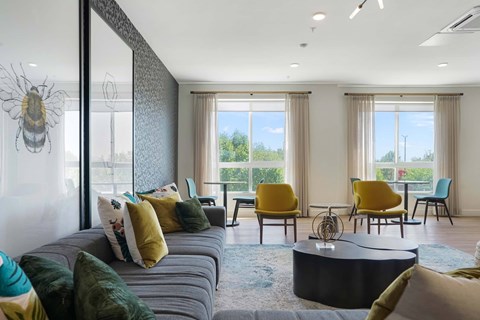 A living room with a grey couch and yellow chairs.
