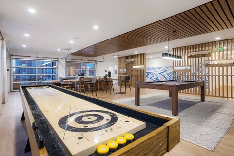 A shiny pool table with a white cloth and yellow balls is in the middle of a room with a wooden ceiling.