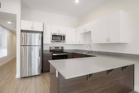 A modern kitchen with a refrigerator, microwave, oven, and cabinets.