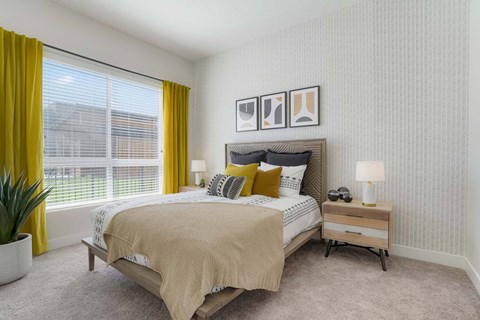 A bedroom with a bed, nightstand, and a window with yellow curtains.