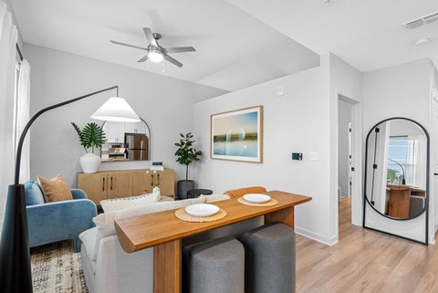 A modern living room with a blue couch, a wooden table, and a painting on the wall.