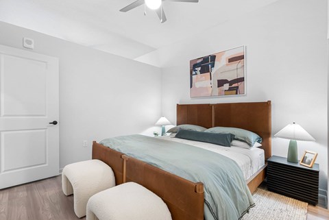 A bedroom with a bed, two lamps, and a painting on the wall.