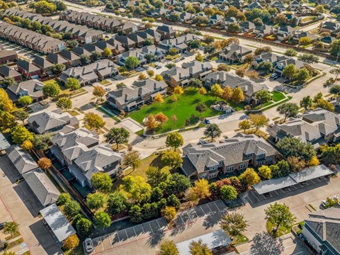 A bird's eye view of a residential neighborhood with houses and a central green space.