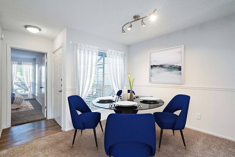 A dining room with a table set for two and a painting on the wall.
