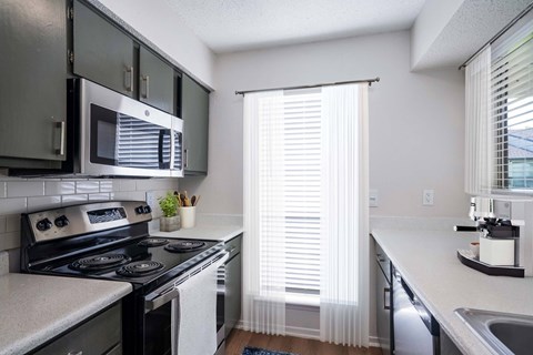 A modern kitchen with a black stove top oven and microwave, white cabinets, and a white countertop.