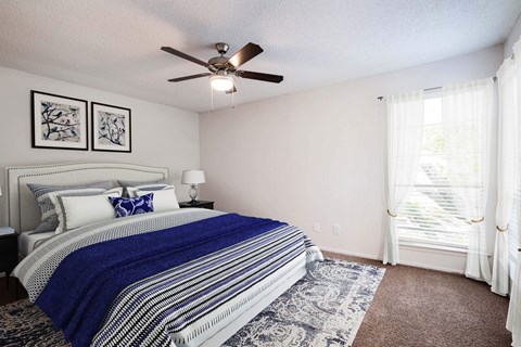 A bedroom with a bed, a ceiling fan, and two pictures on the wall.