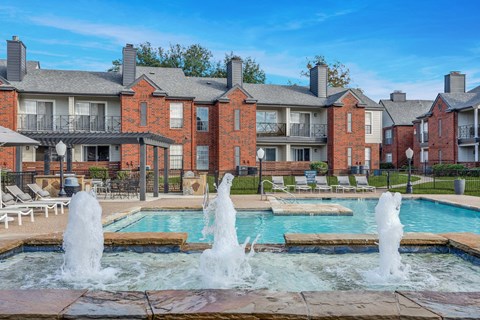 A large red brick building with a pool in front of it.