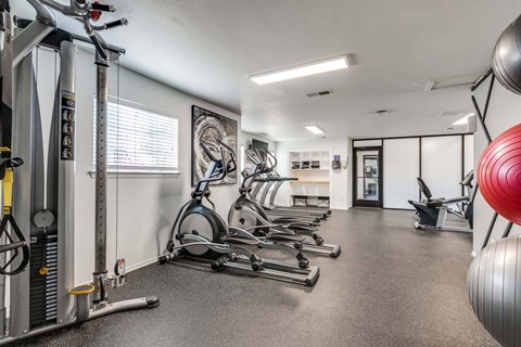 A gym with a variety of exercise equipment including treadmills, stationary bikes, and weight machines.