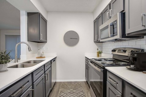 A modern kitchen with dark cabinets and a white countertop.